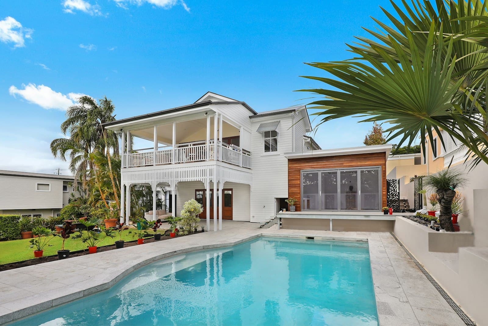 A white Miami home with a pool and palms under a clear sky